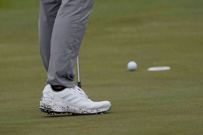 Side view of white adidas golf shoes.